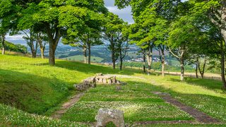 © Rediscovering the Antonine Wall Project
Bar Hill Fort, the remains of the bathhouse. A stone rectangle in the grass. A low stone arch in front. Trees and sky beyond. © Rediscovering the Antonine Wall Project
Bar Hill Fort, the remains of the bathhouse. A stone rectangle in the grass. A low stone arch in front. Trees and sky beyond.