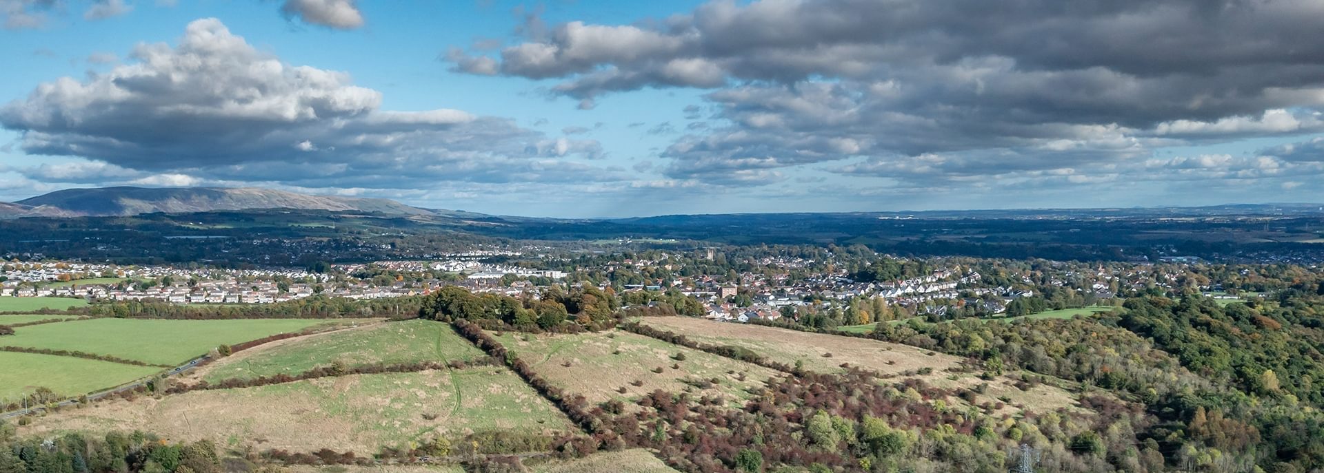 © Rediscovering the Antonine Wall Project
An expansive view of green fields and woodland and a town in the distance. The sky is blue, and full of silver edged clouds. © Rediscovering the Antonine Wall Project
An expansive view of green fields and woodland and a town in the distance. The sky is blue, and full of silver edged clouds.