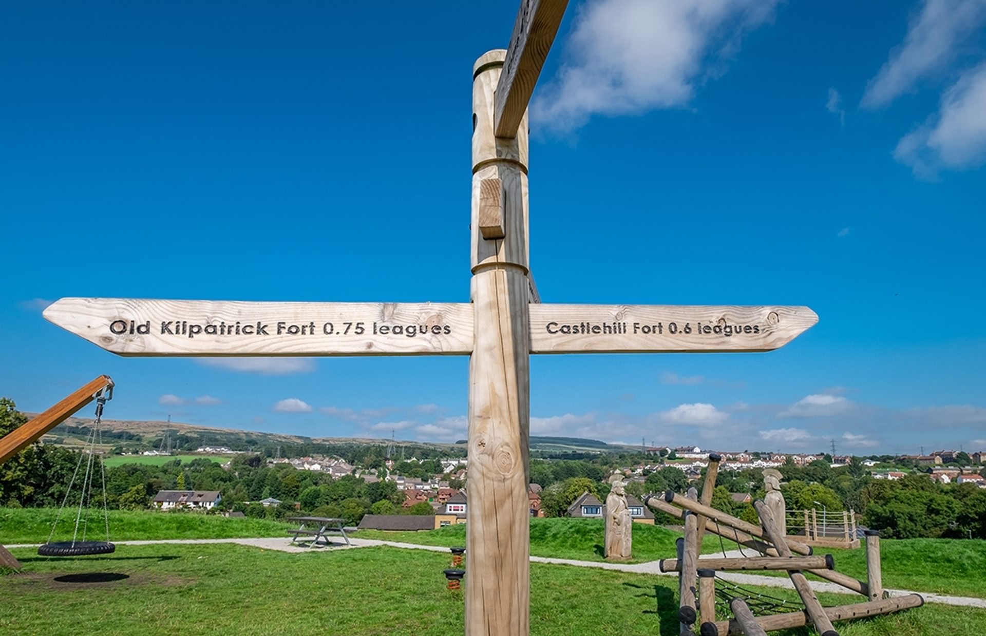© Rediscovering the Antonine Wall Project
Duntocher Fort, Goldenhill Park. A wooden finger sign with the play park behind it on a sunny day. Trees and houses beyond. © Rediscovering the Antonine Wall Project
Duntocher Fort, Goldenhill Park. A wooden finger sign with the play park behind it on a sunny day. Trees and houses beyond.