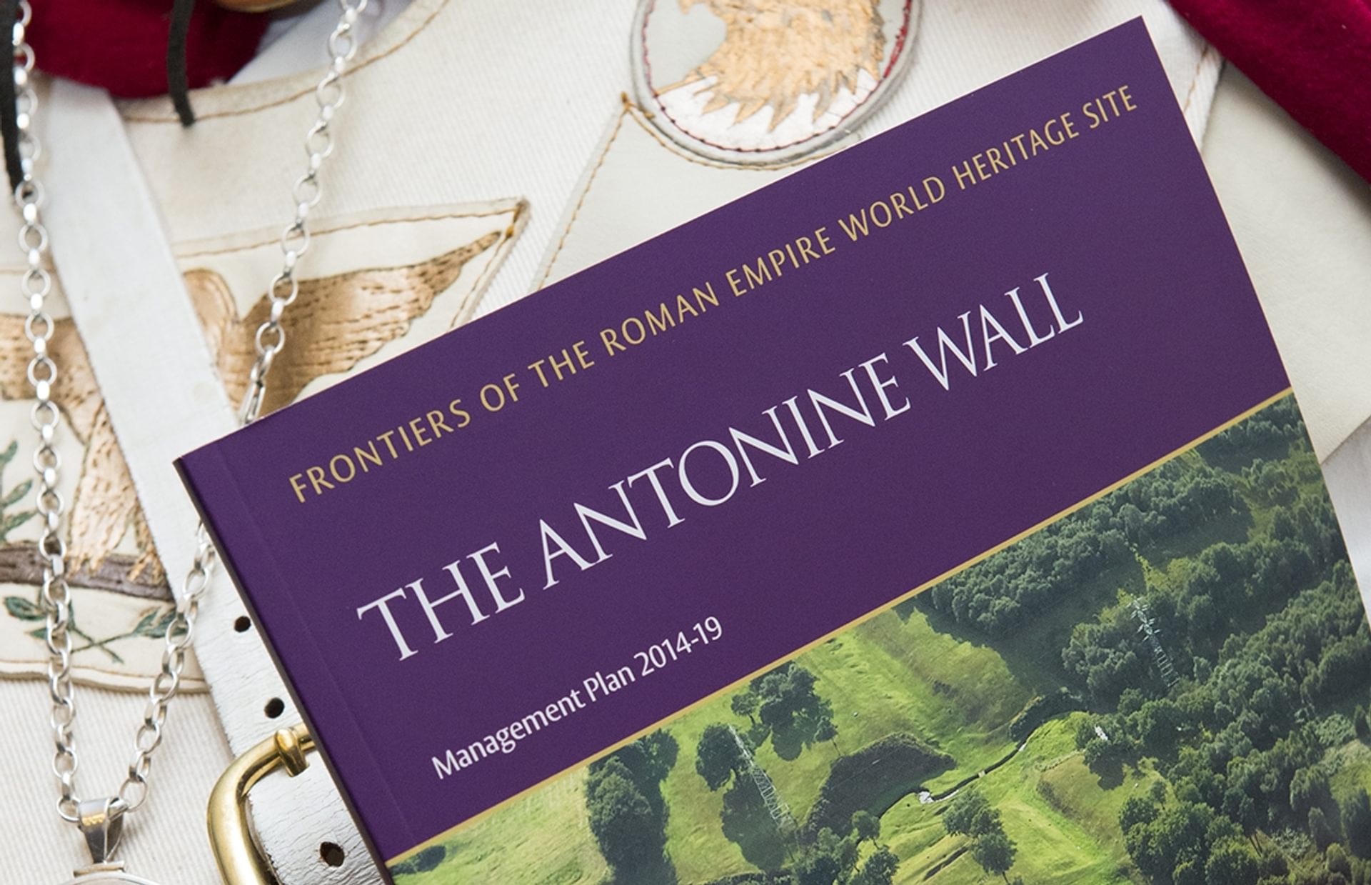 © Crown Copyright HES
A close-up of a person holding the Antonine Wall Management Plan 2014-2019, they are wearing a Roman Centurion costume. © Crown Copyright HES
A close-up of a person holding the Antonine Wall Management Plan 2014-2019, they are wearing a Roman Centurion costume.