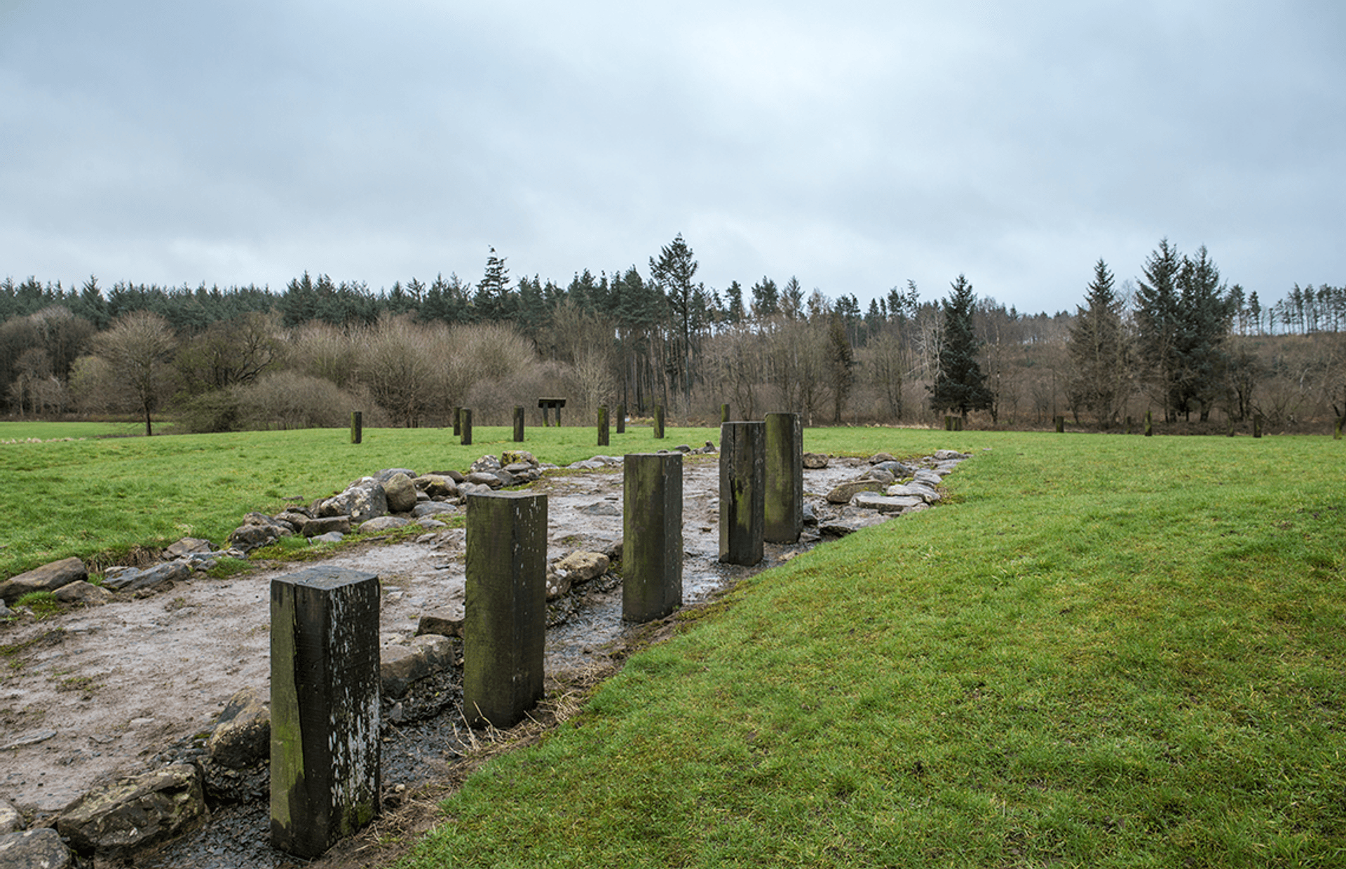 © Marcin Klimek
Kinneil fortlet, a rectangle of low stone kerbing and modern wooden marker posts surrounded by grass, trees, and sky beyond. © Marcin Klimek
Kinneil fortlet, a rectangle of low stone kerbing and modern wooden marker posts surrounded by grass, trees, and sky beyond.
