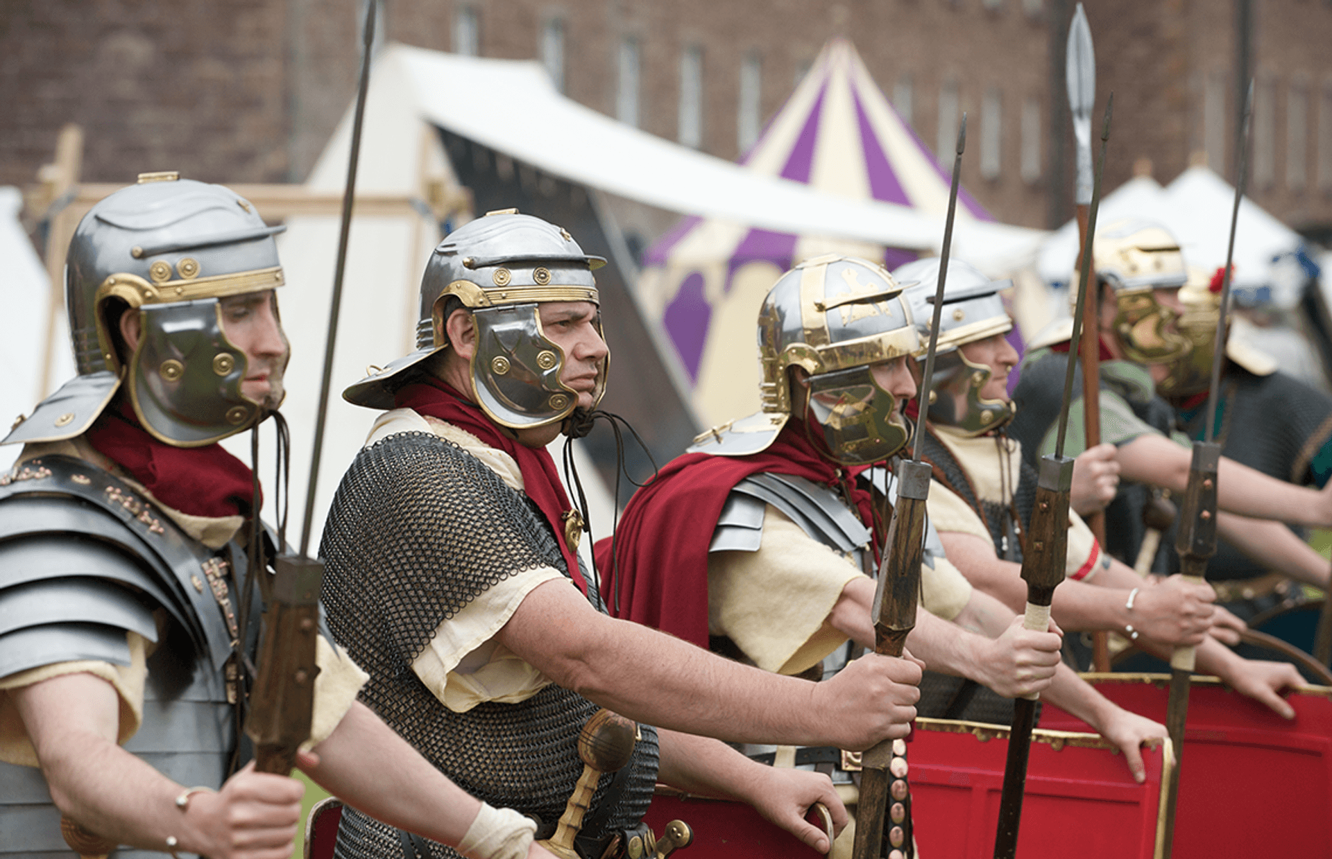 © Rob McDougall
Roman soldiers in metal helmets, chain mail, yellow tunics, and red cloaks, hold javelins. Red shields are in front of them. © Rob McDougall
Roman soldiers in metal helmets, chain mail, yellow tunics, and red cloaks, hold javelins. Red shields are in front of them.