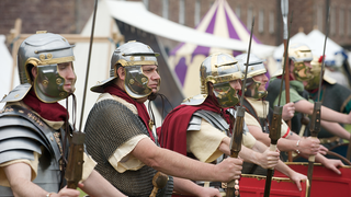 © Rob McDougall
Roman soldiers in metal helmets, chain mail, yellow tunics, and red cloaks, hold javelins. Red shields are in front of them. © Rob McDougall
Roman soldiers in metal helmets, chain mail, yellow tunics, and red cloaks, hold javelins. Red shields are in front of them.