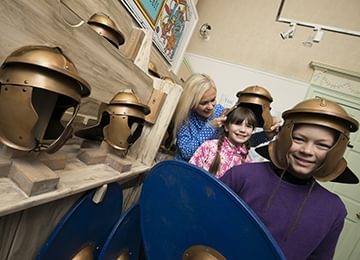 © Crown Copyright HES
The Antonine Wall, Rome’s Northern Frontier gallery, Callendar House. A family of four stand next to replica Roman helmets. © Crown Copyright HES
The Antonine Wall, Rome’s Northern Frontier gallery, Callendar House. A family of four stand next to replica Roman helmets.